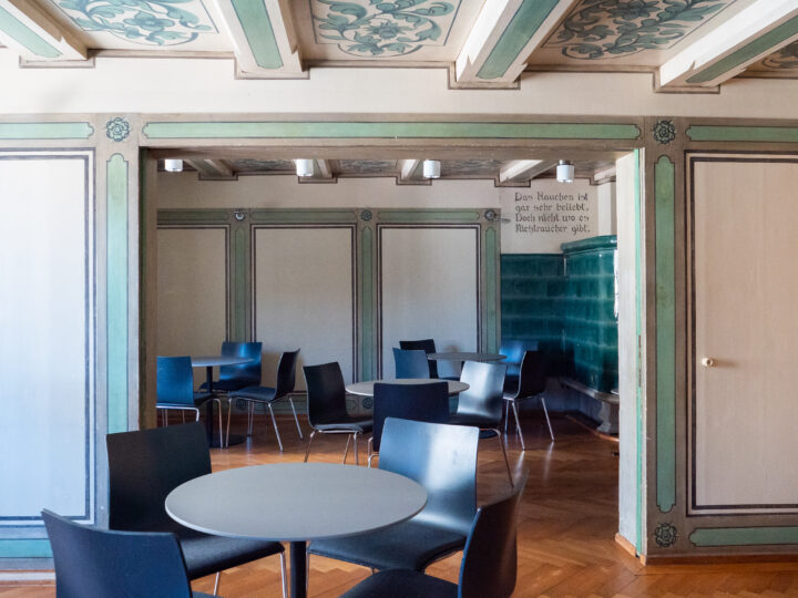 Die Grüne Stube hat Fischgrätenparkett, einen grünen Kachelofen und grüne Wand- und Deckenverzierungen und ist mit runden Tischen mit jeweils drei Stühlen ausgestattet.