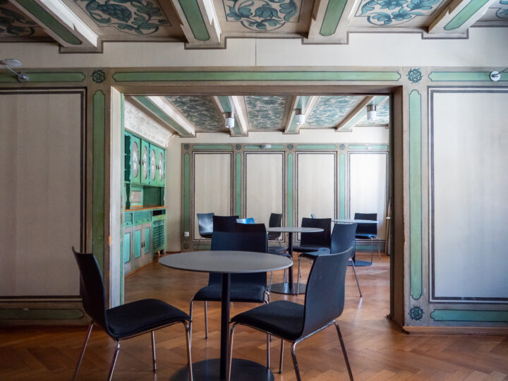 Die Grüne Stube hat Fischgrätenparkett, einen grünen Kachelofen und grüne Wand- und Deckenverzierungen und ist mit runden Tischen mit jeweils drei Stühlen ausgestattet.