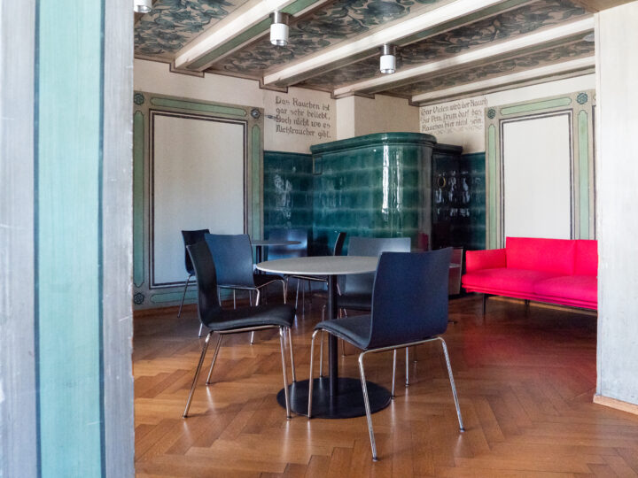 Die Grüne Stube hat Fischgrätenparkett, einen grünen Kachelofen und grüne Wand- und Deckenverzierungen und ist mit runden Tischen mit jeweils drei Stühlen ausgestattet.