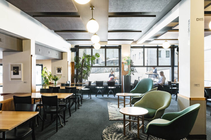 Der obere Teil des Bistros. Es hat einen dunklen Teppichboden, einige gemütliche Sessel,Tische und Stühle. An der hinteren Wand ist ein grosses Fenster.